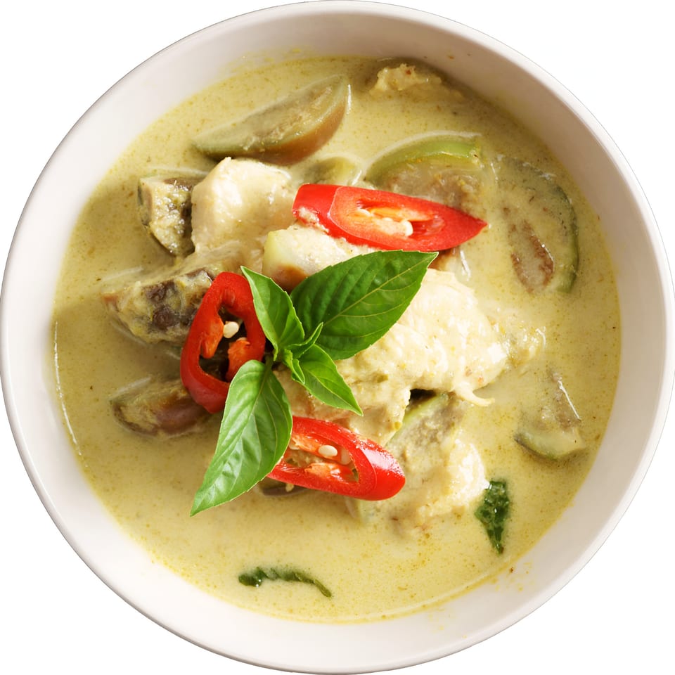 Grace ThaiNY's green curry with chicken, eggplant, red chilies, and basil in a white bowl.